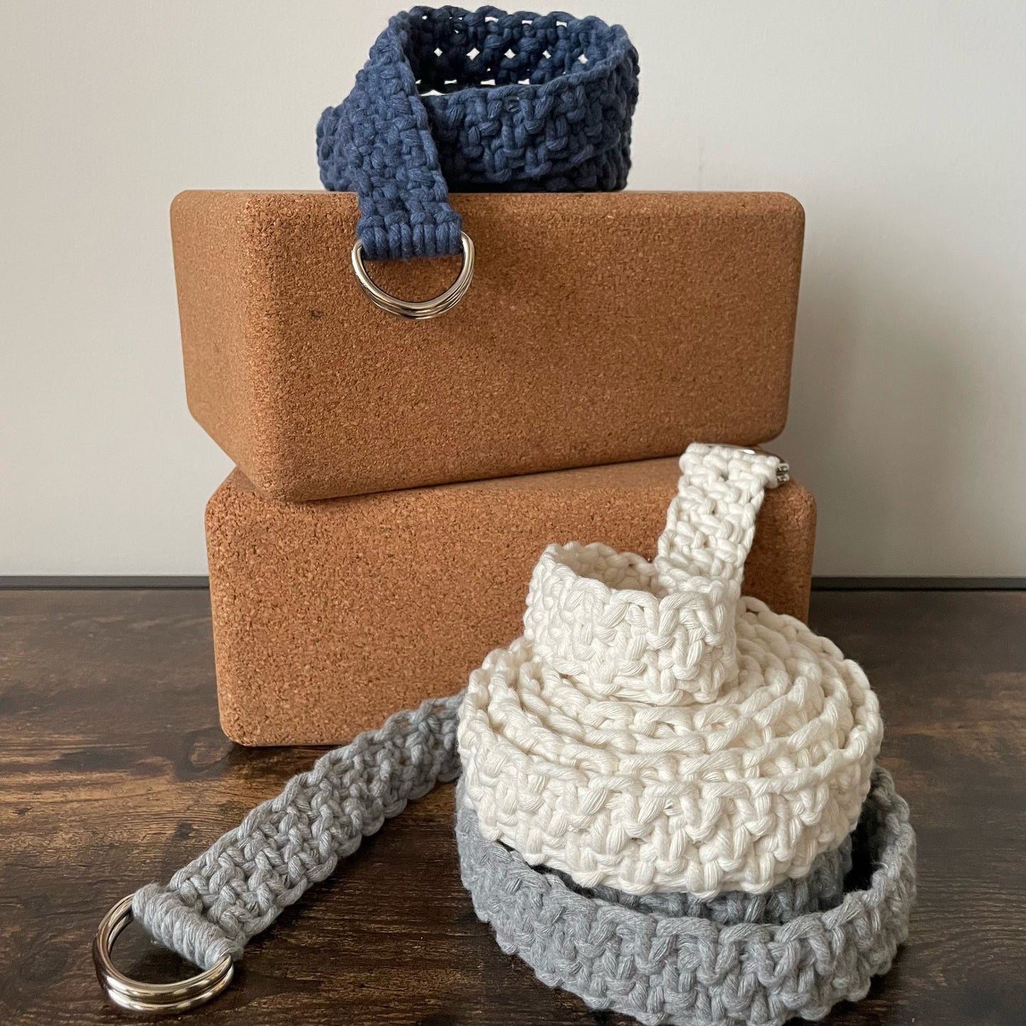 Adjustable Macramé Yoga Strap Prop in Cool Cotton colors, stacked on yoga blocks, light bakground