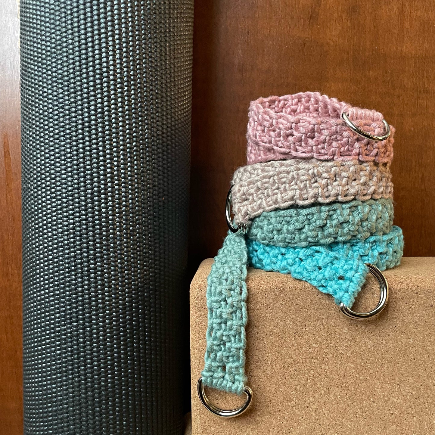 Adjustable Macramé Yoga Straps in Bright Bamboo colors, stacked on yoga blocks, dark background