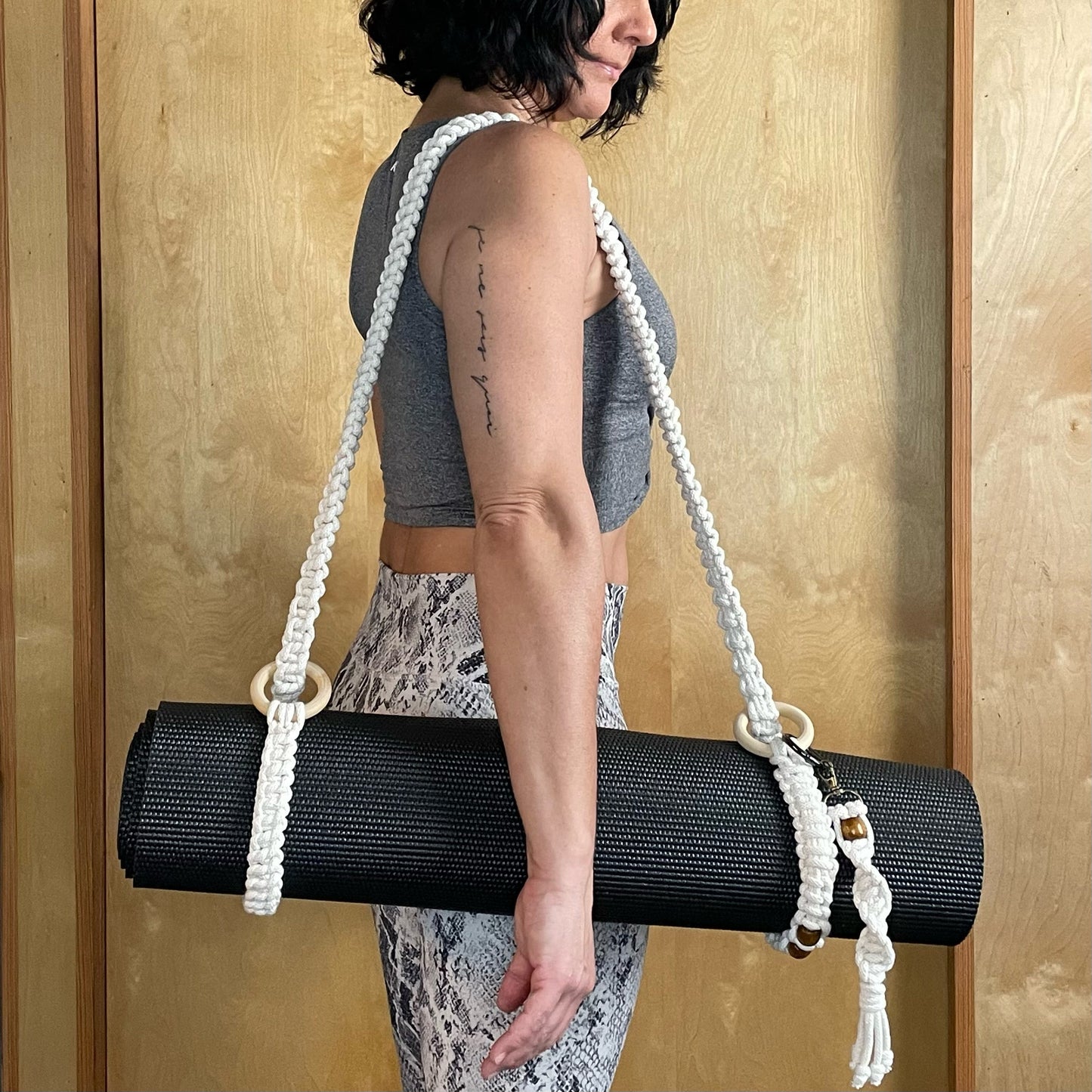Model standing, carrying rolled up mat with Yoga Strap and attached Key Chain.