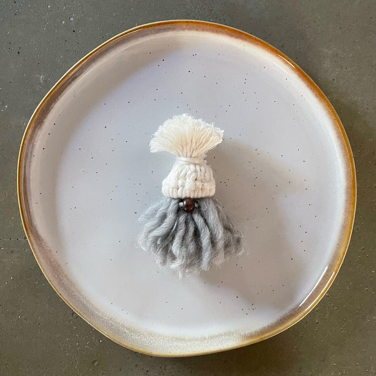 Gnome, pearl-colored hat, dark coffee nose, silver curly beard, centered on dinner plate