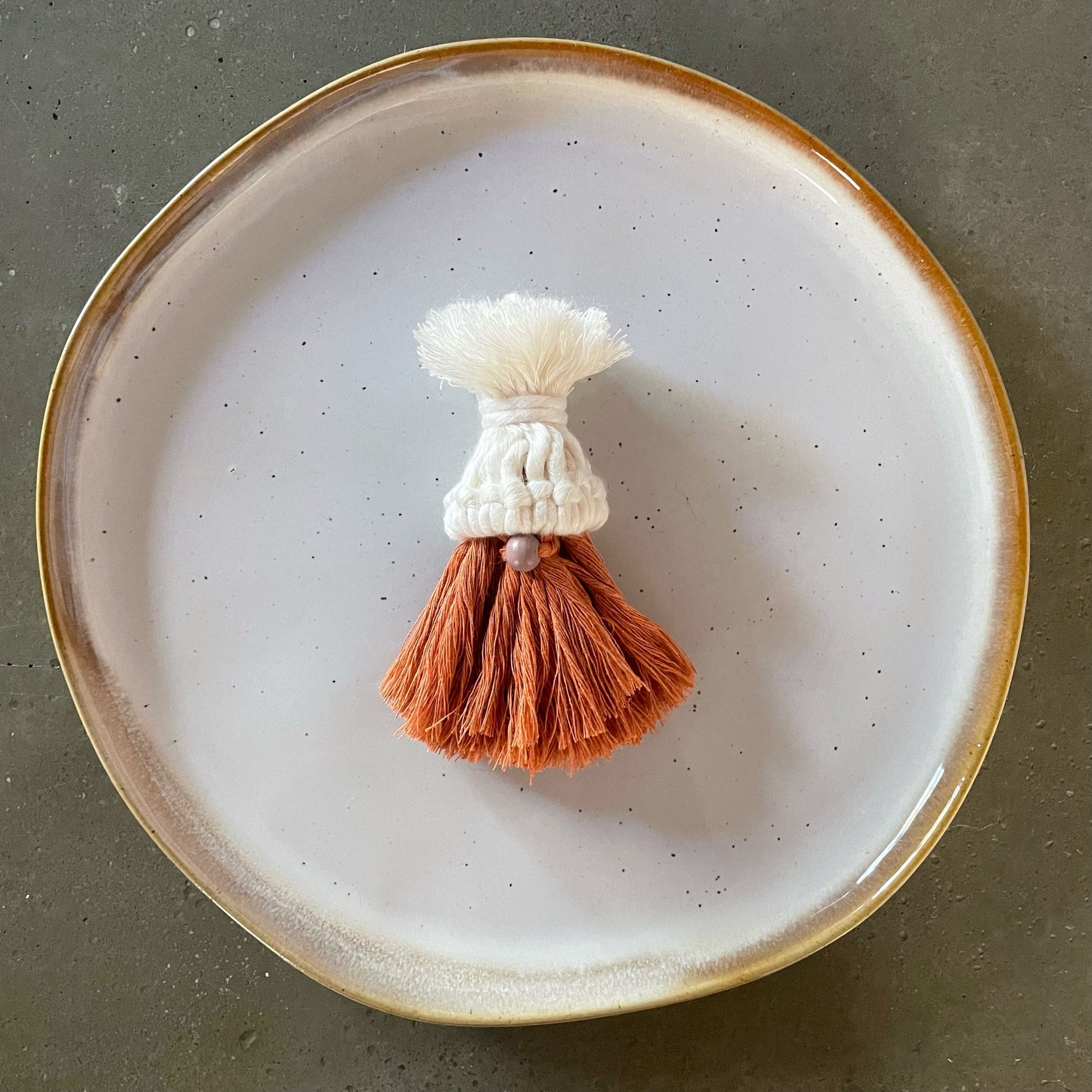 Gnome, pearl-colored hat, mauve nose, terracotta combed beard, centered on dinner plate